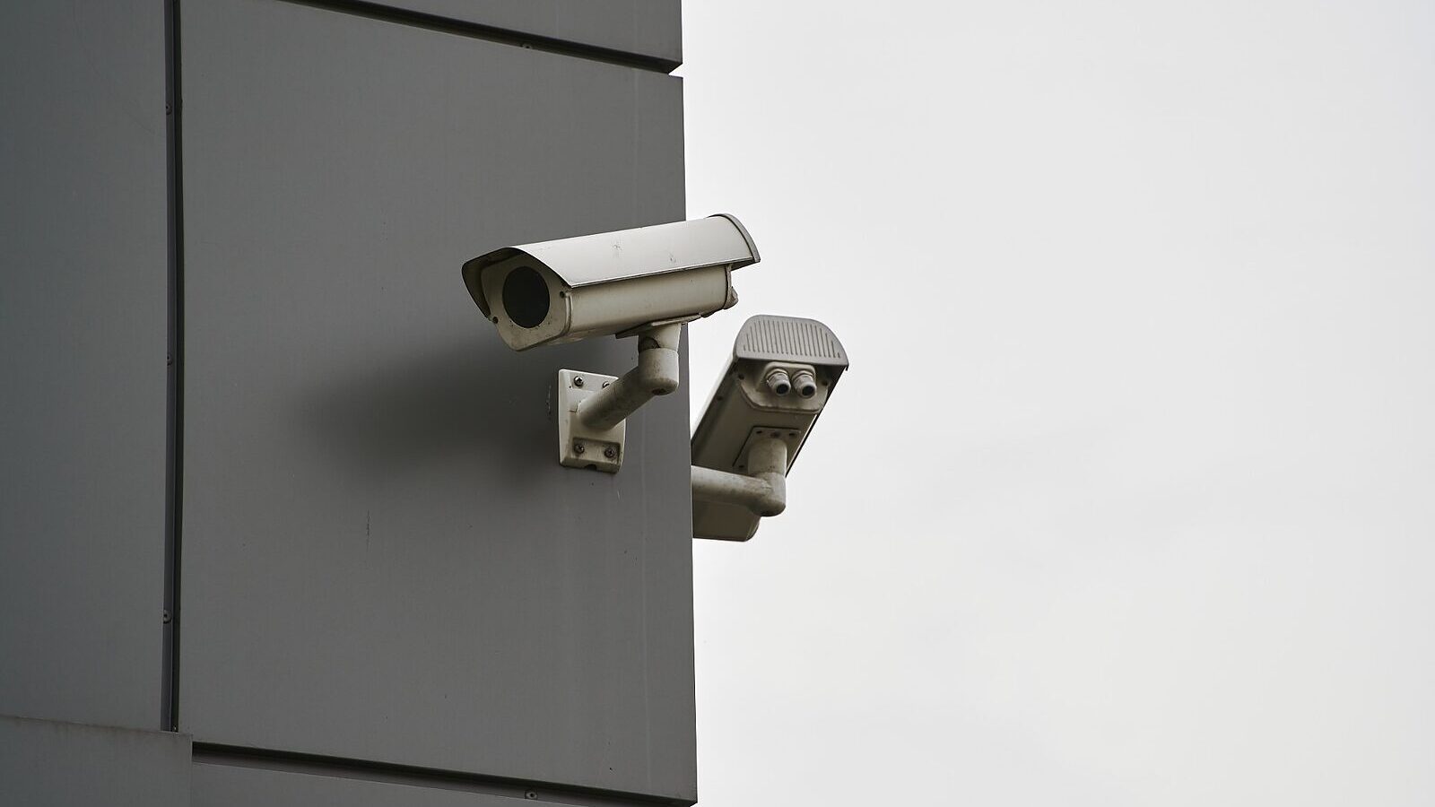 Two surveillance cameras mounted on the corner of a commercial building
