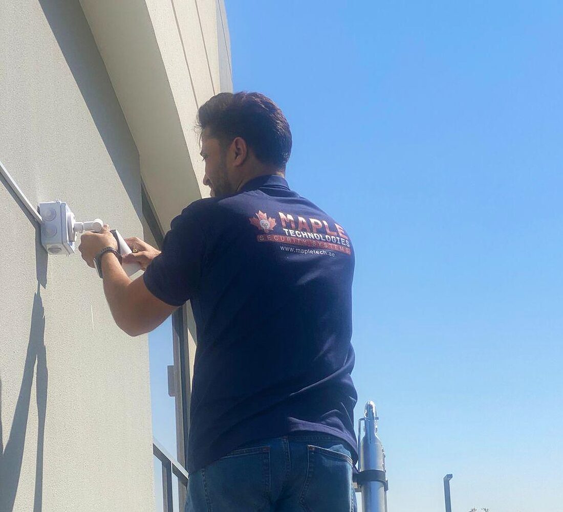 A MapleTech technician fitting a camera to a wall in Dubai